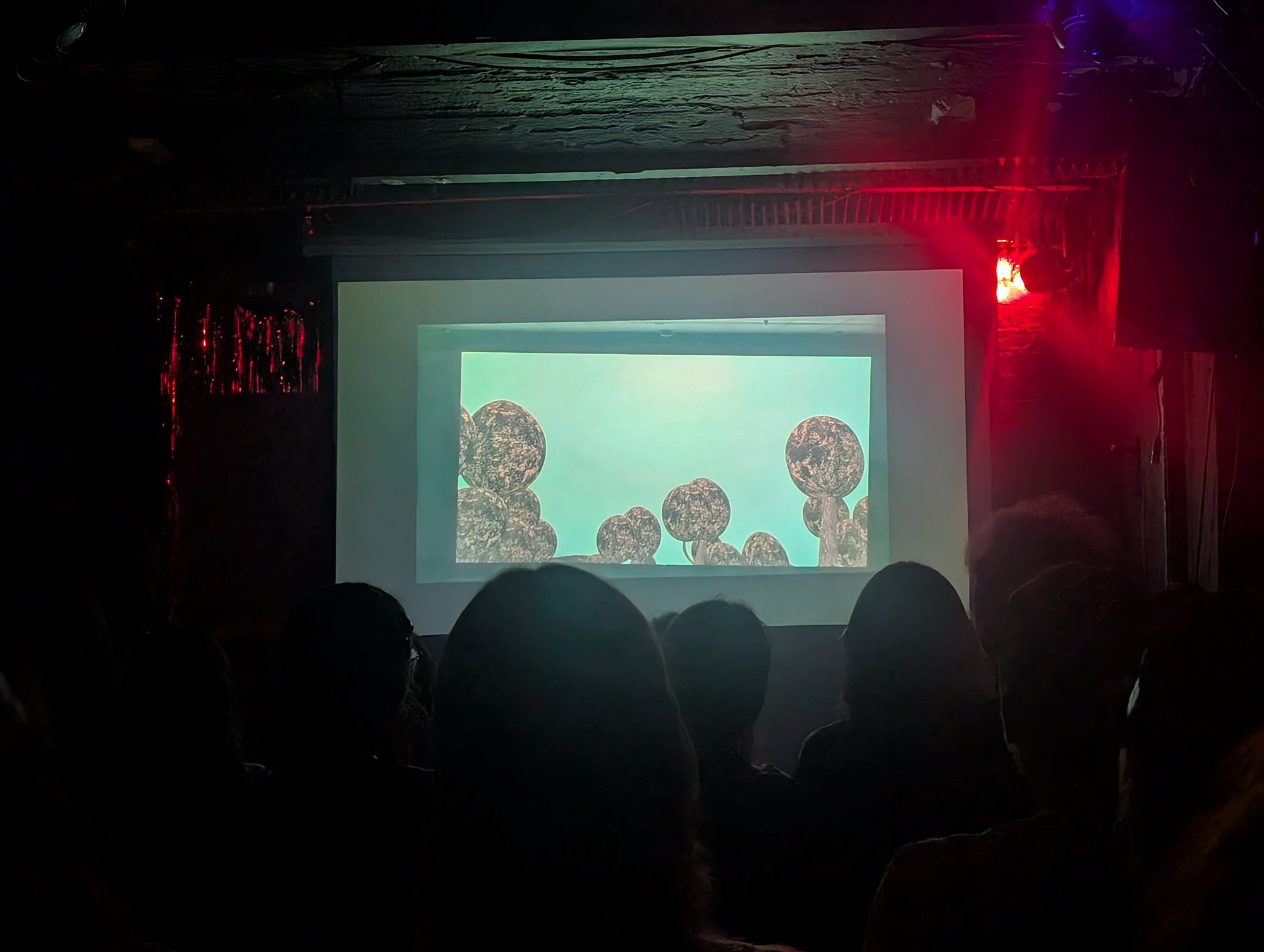 Die Kugelbäume auf der Leinwand, davor die Silhouetten des Publikums