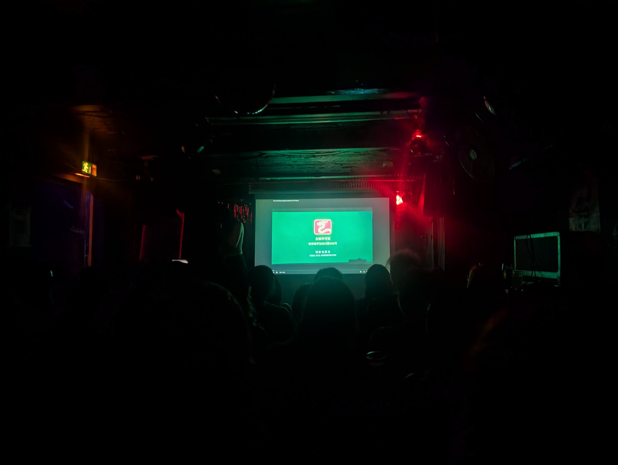 Die Tennis Bar in der Totalen, auf der Leinwand die Vorführlizenz, rechts das Flightcase