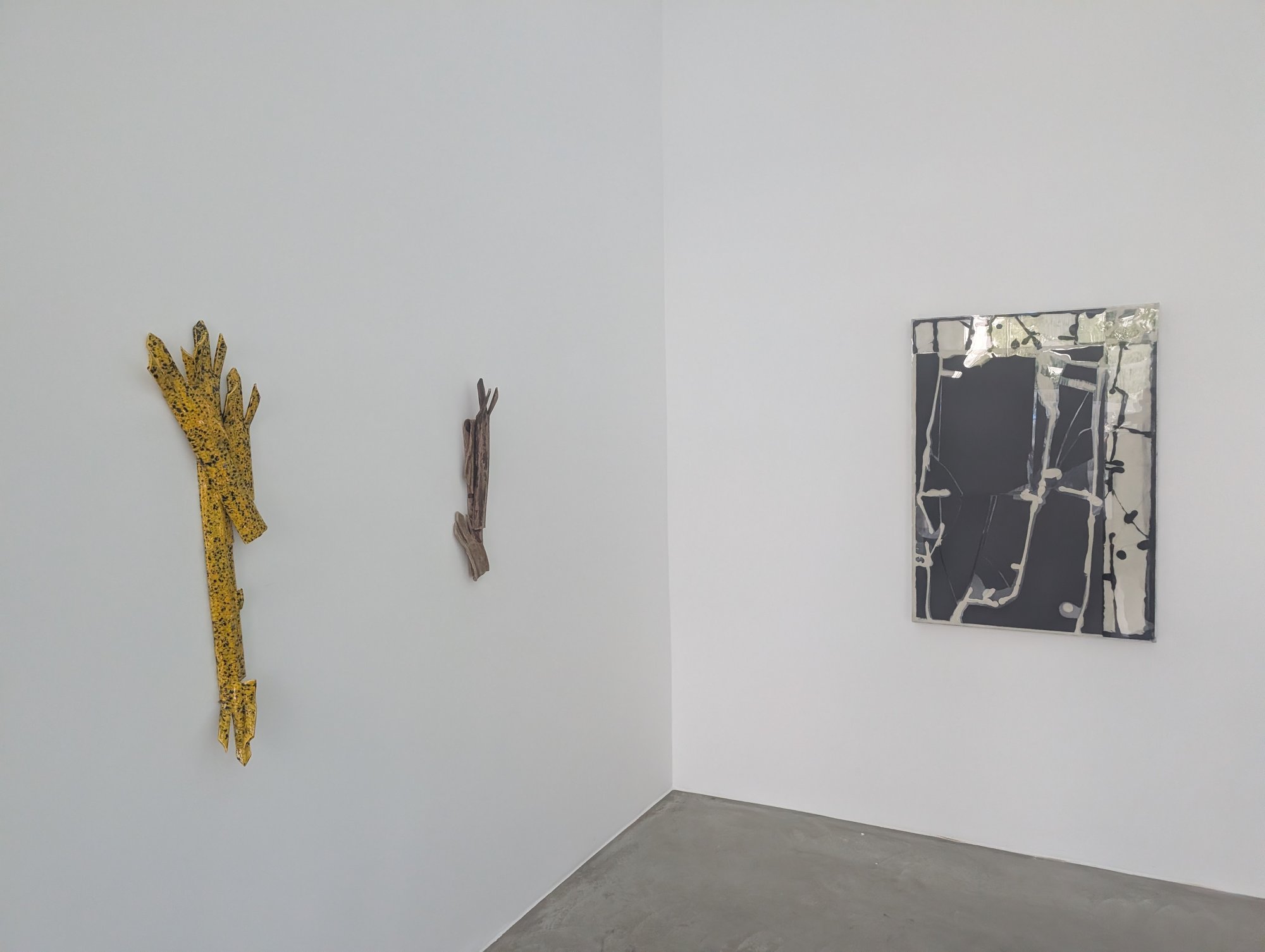 Zwei astförmige Wandobjekte, gelb glasiert und graubraun, daneben eine schwarz glänzende Tafel, „TRACE METALS“ in der galerie burster